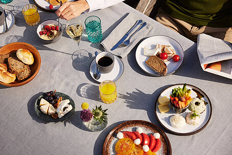 Frühstückstisch mit regionalen Speisen und Blick auf den See.