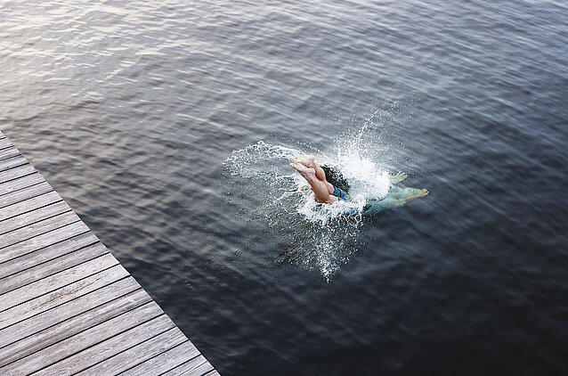 Person springt vom Steg in den Traunsee.